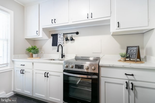 kitchen featuring white cabinets, stainless steel range with electric cooktop, light stone countertops, and sink