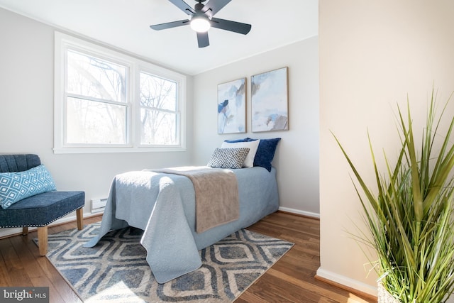 bedroom with a baseboard heating unit, ceiling fan, and dark hardwood / wood-style floors