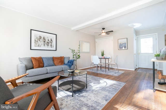 living room featuring dark wood-type flooring, ceiling fan, and beamed ceiling