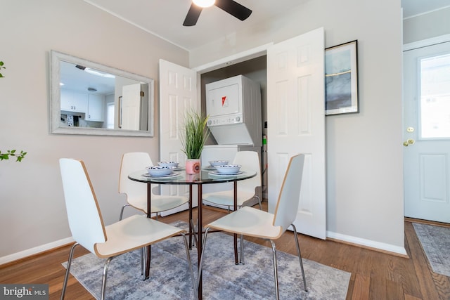 dining room with stacked washer / drying machine, ceiling fan, and hardwood / wood-style flooring