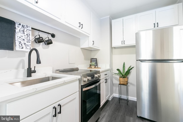 kitchen with stainless steel appliances, light stone countertops, dark wood-type flooring, sink, and white cabinetry