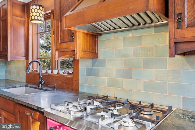 kitchen featuring backsplash, gas stovetop, sink, and premium range hood