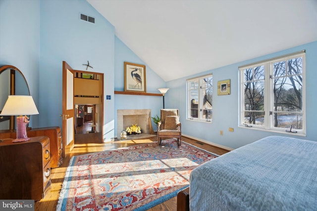 bedroom featuring a fireplace, hardwood / wood-style flooring, and lofted ceiling