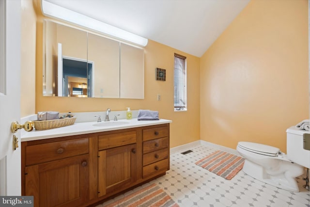 bathroom featuring vanity, lofted ceiling, and toilet