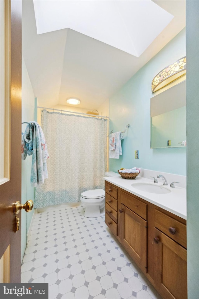 bathroom with vanity, a shower with curtain, a skylight, tile patterned flooring, and toilet