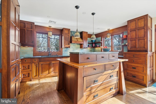 kitchen featuring backsplash, decorative light fixtures, a center island, and sink