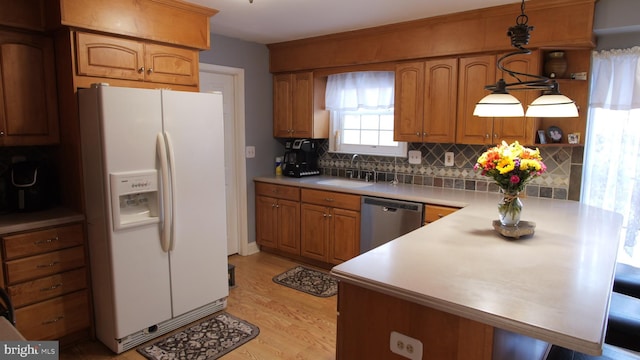 kitchen with sink, stainless steel dishwasher, white refrigerator with ice dispenser, light hardwood / wood-style floors, and decorative light fixtures