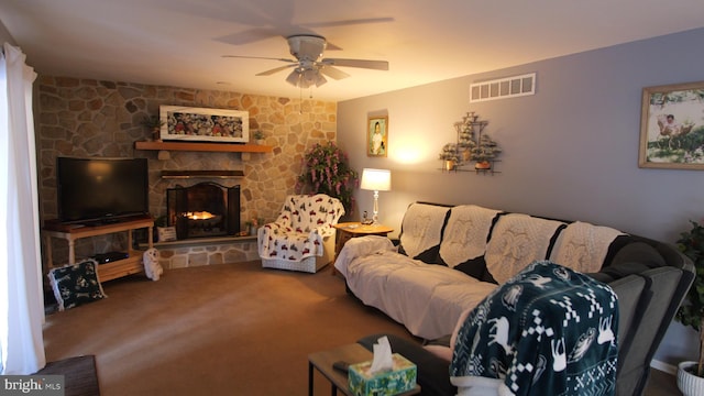 living room featuring ceiling fan, a stone fireplace, and carpet floors