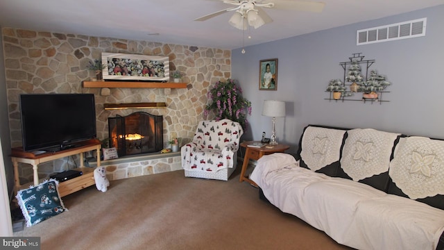 living room with carpet floors, a stone fireplace, and ceiling fan