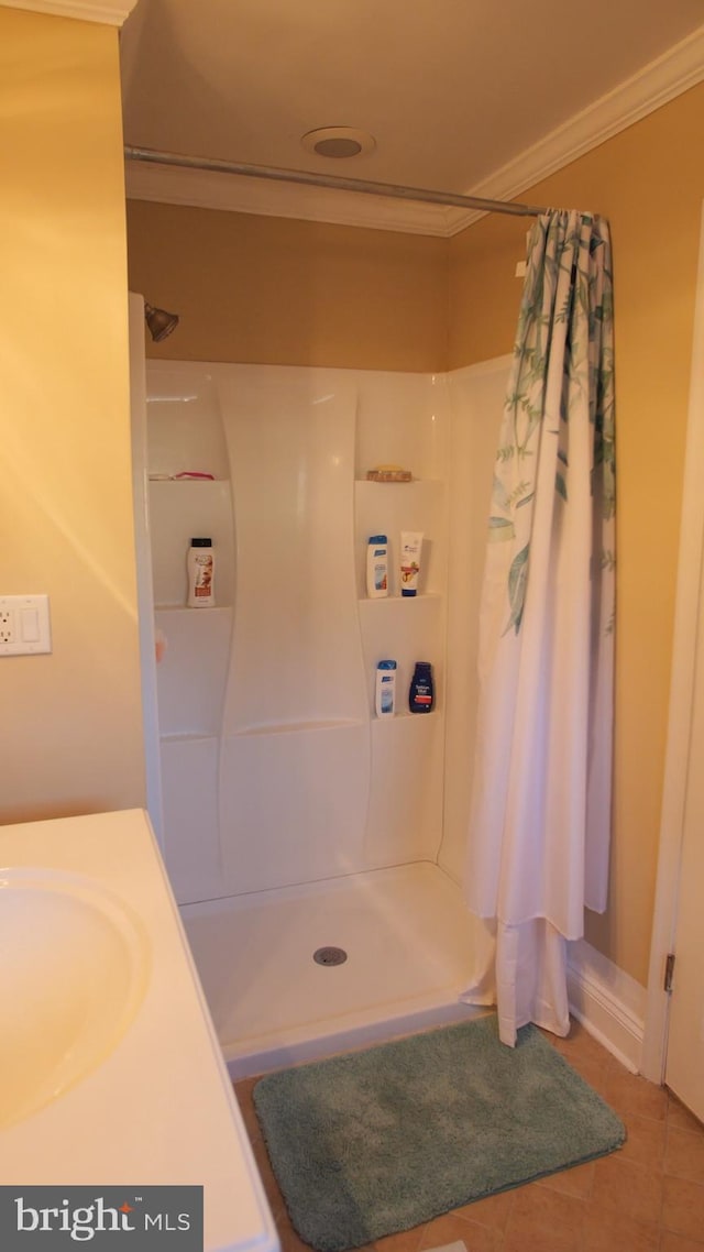 bathroom with a shower with curtain, tile patterned floors, crown molding, and sink