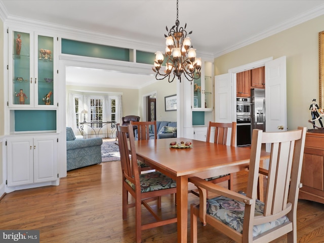 dining area featuring a chandelier, ornamental molding, and light wood-type flooring