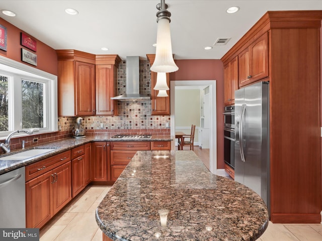 kitchen with visible vents, appliances with stainless steel finishes, a sink, wall chimney range hood, and backsplash