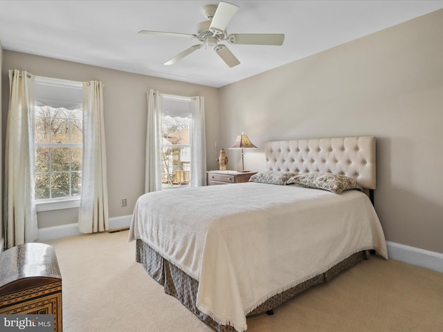 bedroom with light carpet, multiple windows, a ceiling fan, and baseboards