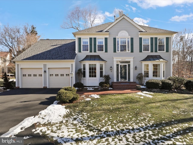 colonial inspired home featuring an attached garage, aphalt driveway, and roof with shingles