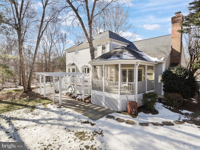 view of front of house with a sunroom, a chimney, and a wooden deck