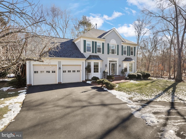 colonial home featuring driveway, a shingled roof, and a garage