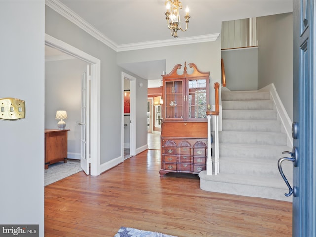 entryway featuring a notable chandelier, wood finished floors, baseboards, stairs, and crown molding