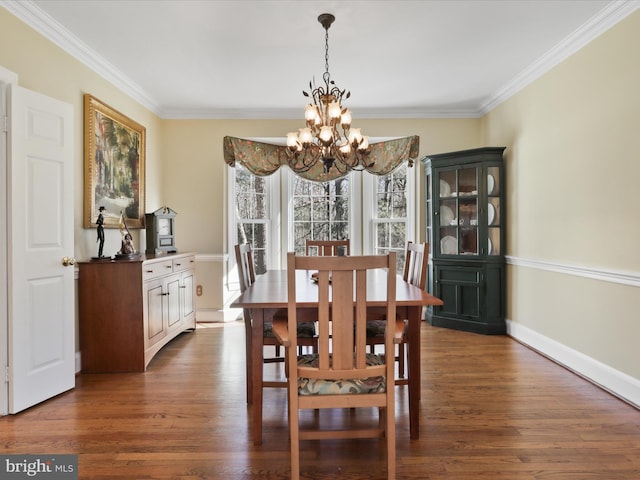 dining room featuring a chandelier, dark wood-type flooring, ornamental molding, and baseboards