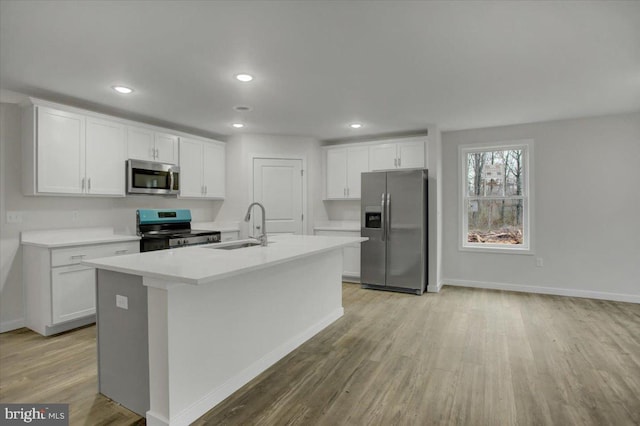 kitchen featuring a center island with sink, sink, white cabinetry, and stainless steel appliances