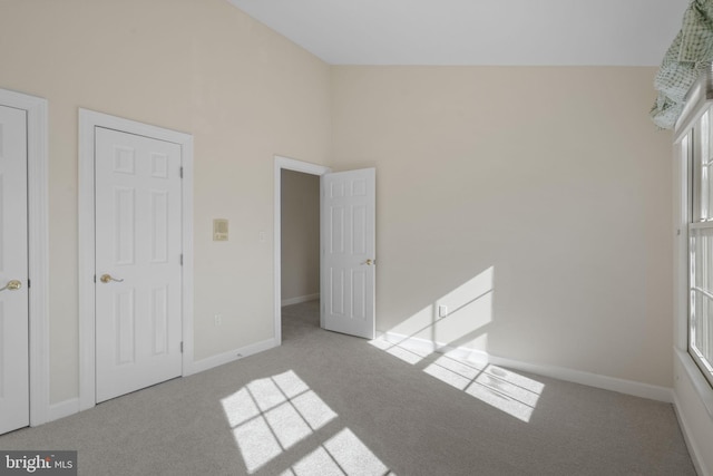 unfurnished bedroom with light colored carpet and high vaulted ceiling