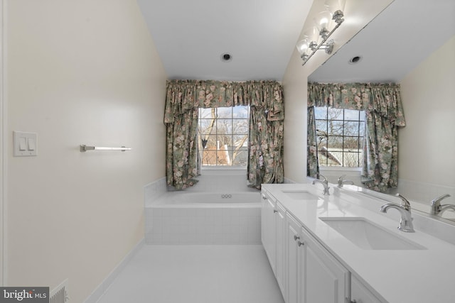 bathroom with tile patterned flooring, vanity, a healthy amount of sunlight, and tiled bath