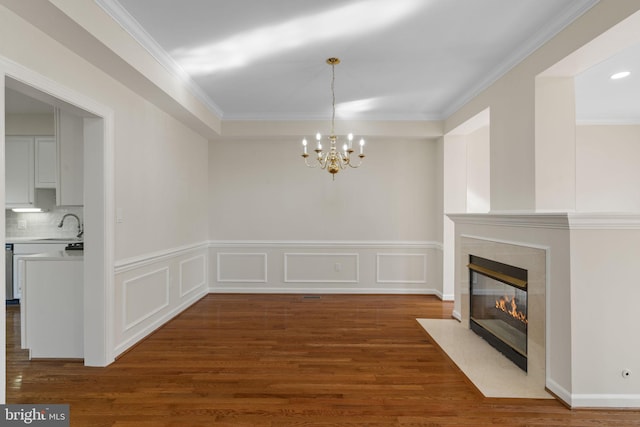 unfurnished dining area with dark wood-type flooring, crown molding, a chandelier, and sink