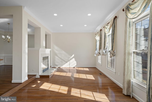 interior space with crown molding, an inviting chandelier, a fireplace, and dark hardwood / wood-style flooring