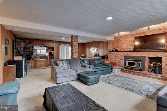 living room featuring ornate columns, a fireplace, wooden walls, light colored carpet, and a textured ceiling