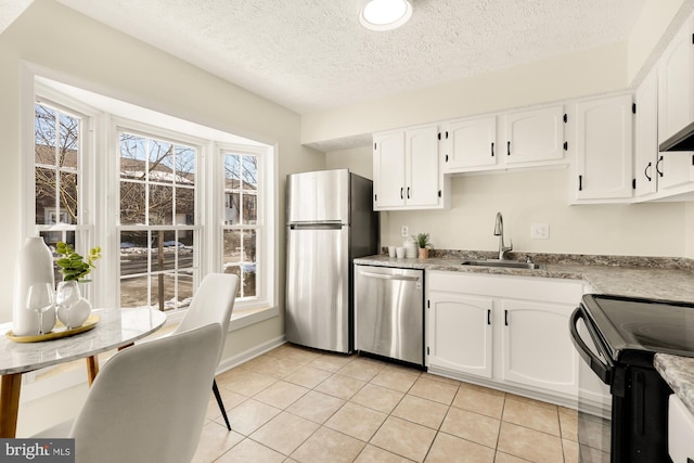 kitchen featuring stainless steel appliances, light tile patterned floors, white cabinets, and sink