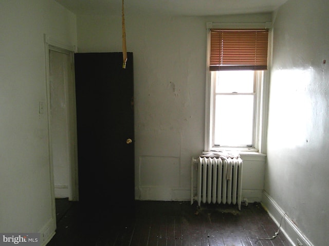 spare room with dark hardwood / wood-style flooring and radiator