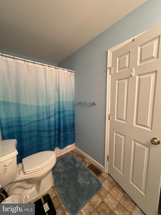 bathroom with a shower with curtain and toilet