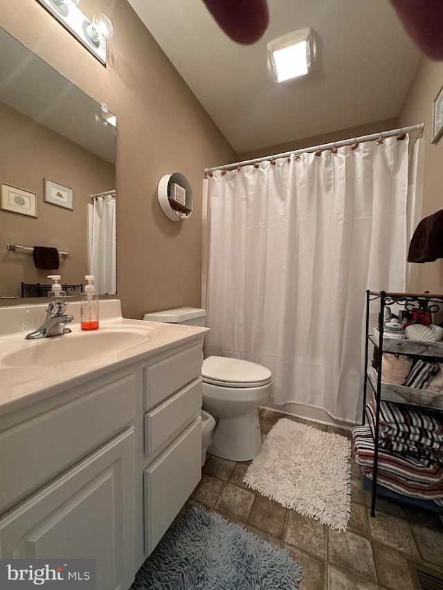 bathroom with vanity, vaulted ceiling, and toilet