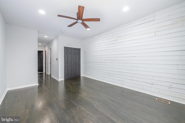 unfurnished room with wood walls, dark hardwood / wood-style floors, and ceiling fan