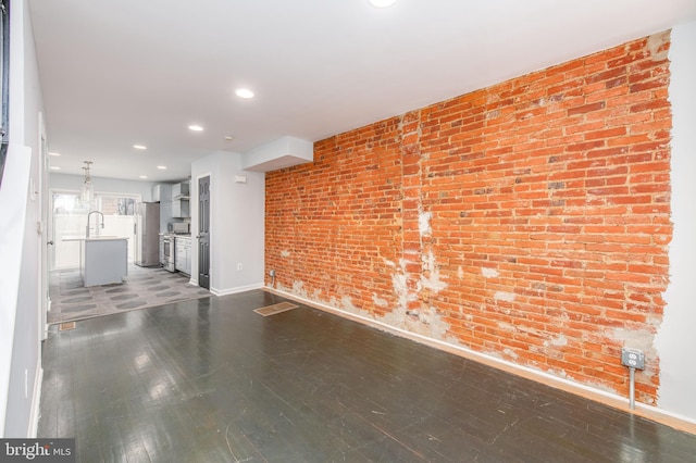 unfurnished living room featuring sink and brick wall