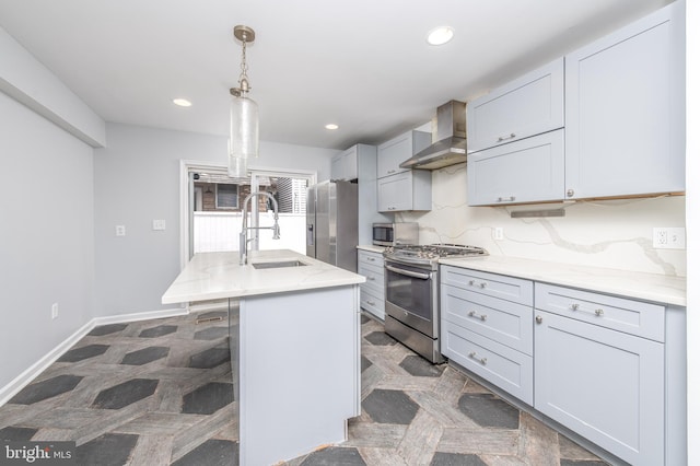 kitchen featuring sink, wall chimney exhaust hood, hanging light fixtures, stainless steel appliances, and a center island with sink