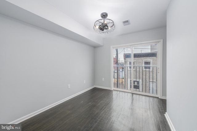 unfurnished room featuring dark hardwood / wood-style floors and an inviting chandelier