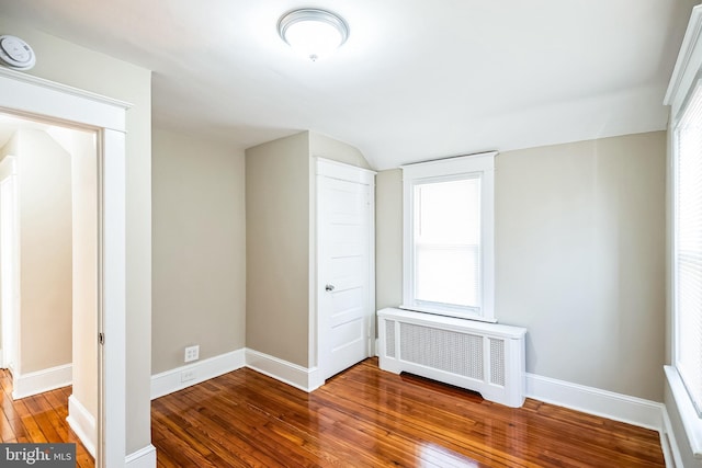 unfurnished bedroom featuring radiator and hardwood / wood-style flooring