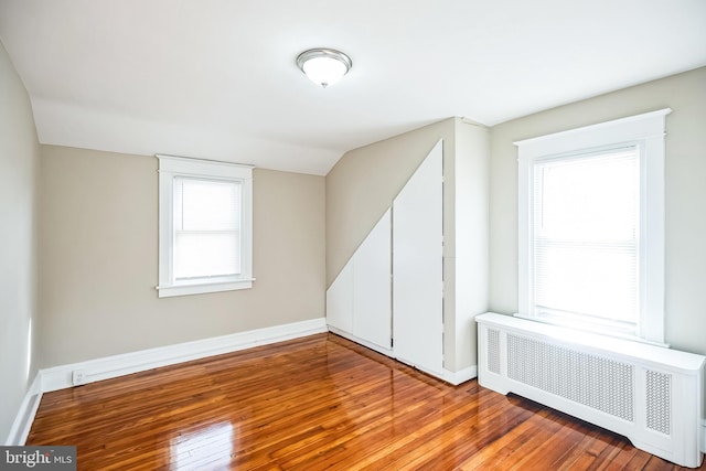 interior space featuring radiator heating unit, lofted ceiling, and hardwood / wood-style flooring