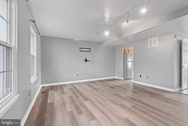 spare room with track lighting and light hardwood / wood-style flooring