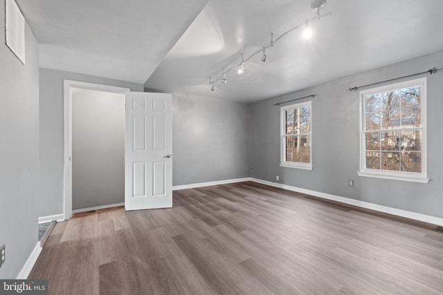 unfurnished room featuring track lighting and hardwood / wood-style flooring