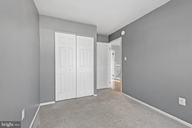 unfurnished bedroom with light carpet and a closet