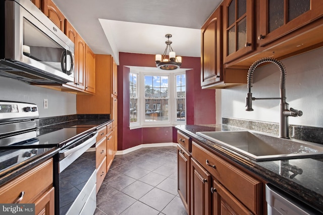 kitchen with sink, tile patterned floors, dark stone counters, decorative light fixtures, and appliances with stainless steel finishes