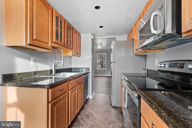 kitchen with dark stone countertops, sink, dark tile patterned floors, and stainless steel appliances