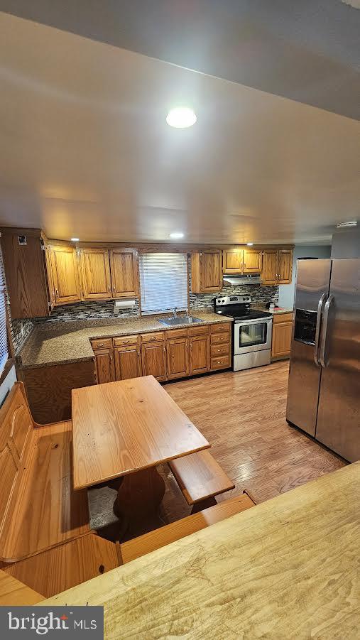 kitchen featuring tasteful backsplash, sink, light wood-type flooring, and appliances with stainless steel finishes