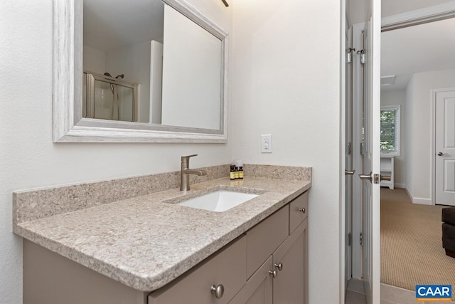 bathroom featuring a shower with door and vanity