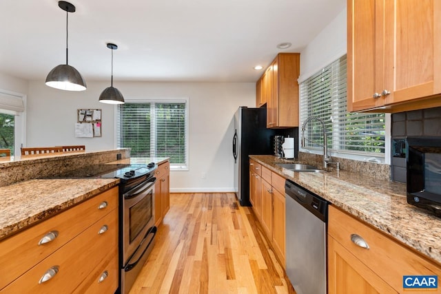 kitchen featuring hanging light fixtures, light stone counters, sink, and stainless steel appliances