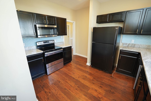 kitchen featuring decorative backsplash, light stone counters, dark hardwood / wood-style floors, and appliances with stainless steel finishes