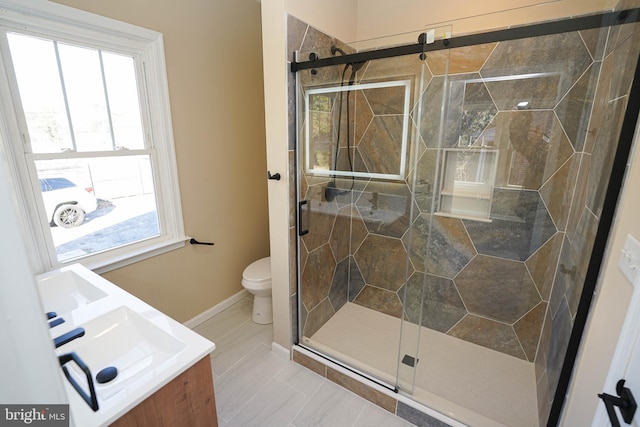 bathroom featuring vanity, a healthy amount of sunlight, an enclosed shower, and toilet