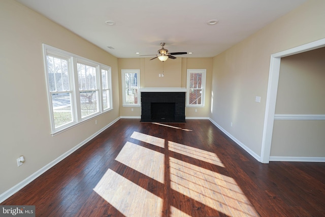 unfurnished living room featuring ceiling fan, dark wood-type flooring, and a brick fireplace