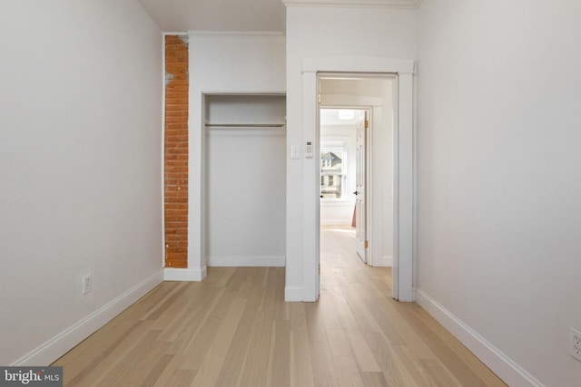 unfurnished bedroom with light hardwood / wood-style flooring, a closet, and ornamental molding